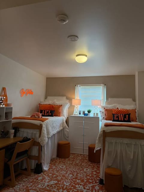 a dim lit room in the University Commons with orange decorative pillows, a glowing sign that says